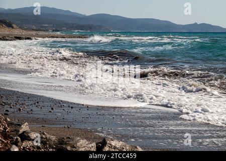 Vista panoramica sulla costa con spiaggia di ciottoli e onde d'acqua sul lato ovest dell'isola greca di Rodi tra Kamiros e Mandriko Foto Stock