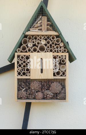 Vista frontale ravvicinata del tavolo degli uccelli in legno dal design intricato con tetto ad apice verde, con sezioni di coni di pino e pezzi circolari di legno, da vicino Foto Stock