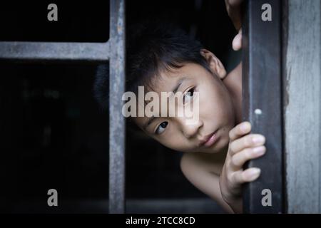 Il bambino ha catturato la gabbia di ferro con tristezza e disperazione. Il concetto di fermare la violenza contro i bambini e la tratta di esseri umani. Foto Stock