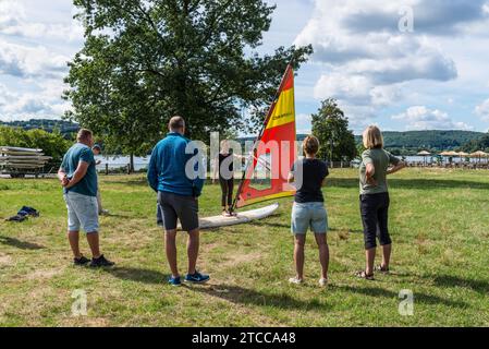 Bochum, Germania - 6 agosto 2022: La gente tiene una lezione di windsurf con un istruttore sulla riva del lago Kemnader vicino a Bochum, North Rhine-Westp Foto Stock