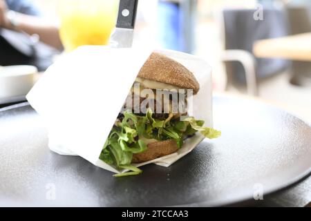 Un primo piano di un panino appena fatto su un piatto, tagliato in due da un coltello Foto Stock