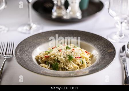 Spaghetti italiani Algio e olio con aglio parmigiano e peperoncino al tavolo festivo del ristorante. Foto Stock