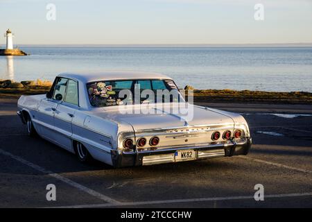 Auto d'epoca americana, Chevrolet Impala del 1964, dietro il lago Vaettern e il faro di Hjo, Hjo, Vaestra Goetaland, Svezia Foto Stock