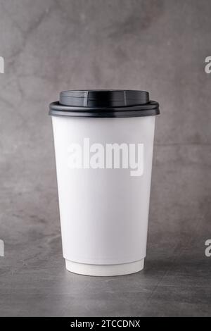 Tazza in carta bianca da asporto con coperchi in plastica nera isolati su sfondo grigio Foto Stock