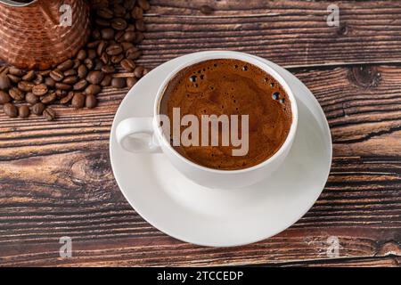 Doppio caffè turco in una tazza di porcellana bianca con caffettiera decorativa su un tavolo di legno Foto Stock