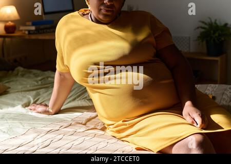 Primo piano di una donna incinta afroamericana che riposa sul letto a casa Foto Stock