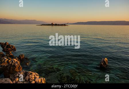 Crepuscolo sull'isola di San Marino al largo della costa adriatica di Novi Vinodolski, Primorje-Gorski Kotar, Croazia. Metà settembre. Cappella SV Martina sull'isola Foto Stock