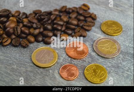 Chicchi di caffè con monete in euro, aumento del prezzo del caffè Foto Stock