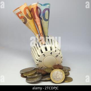 Valvola termostatica di un riscaldatore con banconote e monete Euro, simbolo immagine costi di riscaldamento Foto Stock