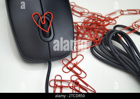 mouse per computer con graffette rosse, una delle quali a forma di cuore, amore in ufficio Foto Stock