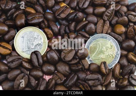 Chicchi di caffè con monete in euro, aumento del prezzo del caffè Foto Stock