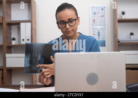 Videochiamata medica, visualizzazione di pellicole radiografiche sul computer portatile e spiegazione al paziente in telemedicina. Foto Stock