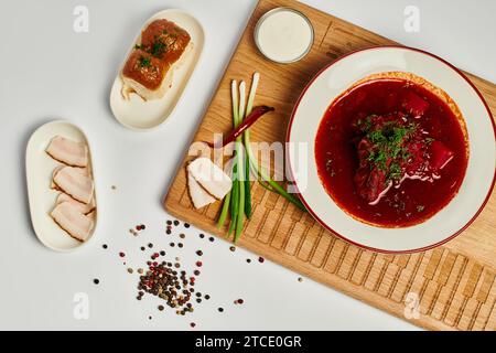 Borsch ucraino tradizionale vicino a panini all'aglio, strutto di maiale e panna acida su tagliere, vista dall'alto Foto Stock