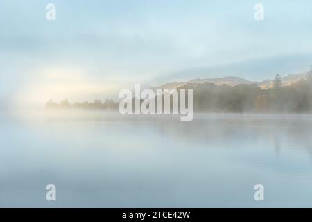 Riflessi autunnali di Misty al mattino presto sull'acqua di Coniston prelevati dalla testa del lago Foto Stock