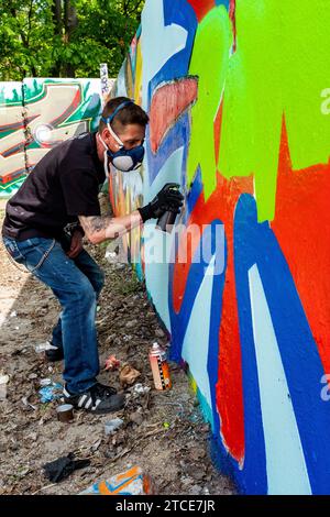 Berlino, Germania. Artista di graffiti che crea jet un'altra opera d'arte urbana su parti dell'ex muro di Berlino, al confine con l'ex Germania Est o DDR. Foto Stock