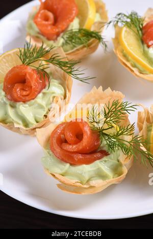 Avocado montato con crema di formaggio soffice nella mousse più delicata, una fetta di salmone e limone. Servita in cesti croccanti con pasta phyllo cotta al forno Foto Stock