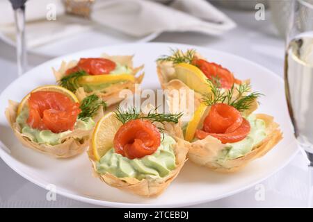 Avocado montato con crema di formaggio soffice nella mousse più delicata, una fetta di salmone e limone. Servita in cesti croccanti con pasta phyllo cotta al forno Foto Stock