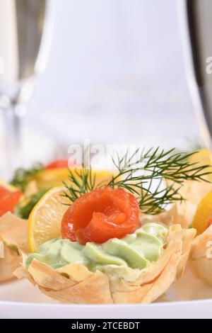 Avocado montato con crema di formaggio soffice nella mousse più delicata, una fetta di salmone e limone. Servita in cesti croccanti con pasta phyllo cotta al forno Foto Stock