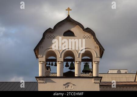 Il campanile della Chiesa ortodossa illuminato dal sole che tramonta contro un cielo cupo. Foto Stock