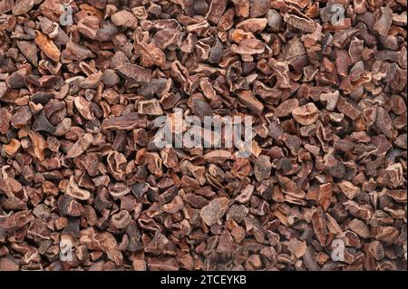 Pennini di cacao. Fondo con chicchi di cacao secchi e fermentati tritati, semi di Theobroma cacao, generalmente trasformati in cioccolato. Foto Stock