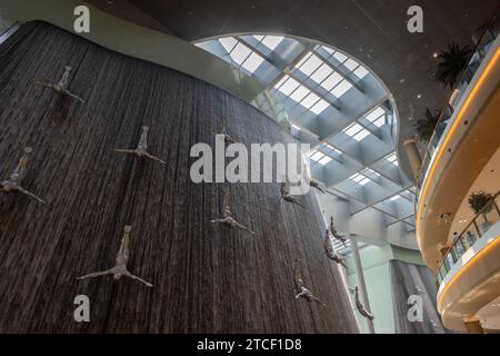 Dubai, Emirati Arabi Uniti, 15 ottobre 2023: L'iconica scultura a cascata umana al Dubai Mall, con subacquei a grandezza naturale che scendono da una fontana interna a più piani Foto Stock