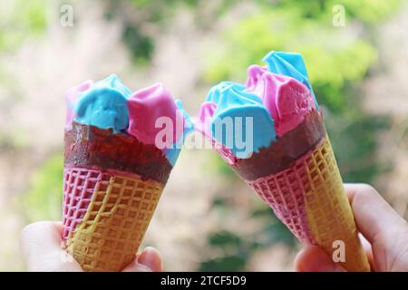 Due coni di gelato rosa e blu che si accendono su sfondo verde Foto Stock