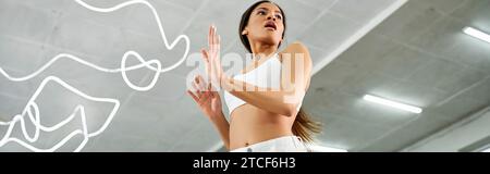 donna artistica afroamericana in bianco sport top prove in studio moderno, banner orizzontale Foto Stock