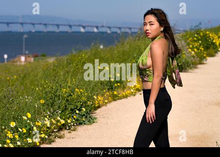 Windy Wind Blown Young Asian Woman Curvy Athletic Standing con San Francisco Bay sullo sfondo Foto Stock