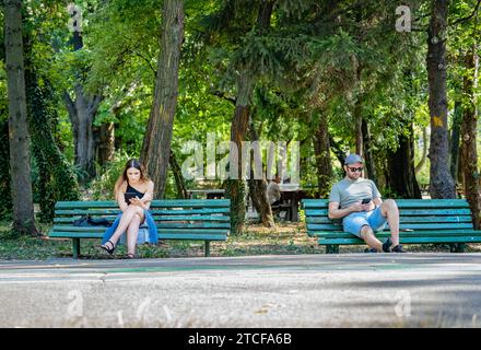 Bucarest, Romania - 17 giugno 2023: Due giovani seduti sulle panchine nel parco Re Mihai I. Foto Stock