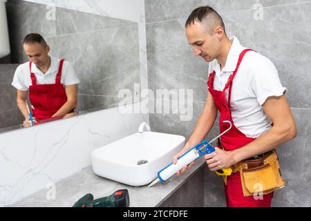 servizio idraulico. Ritratto idraulico vicino all'installazione del sifone del lavabo. Foto Stock