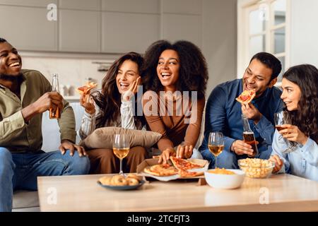 Gruppo spensierato di amici studenti che fanno festa con pizza al coperto Foto Stock