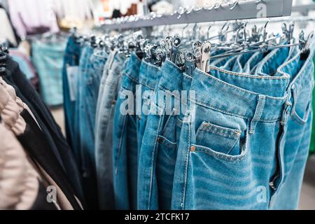 Un paio di jeans blu alla moda esposti su un elegante appendiabiti, appesi in un elegante e moderno ambiente boutique di moda, che rappresentano le ultime novità in termini di abbigliamento casual tr Foto Stock