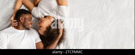 Una coppia afro-americana amorevole sdraiata a letto che ha un momento intimo Foto Stock