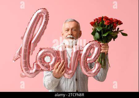 Uomo maturo con bouquet di rose e mongolfiera a forma di AMORE PER le parole su sfondo rosa. Festa di San Valentino Foto Stock