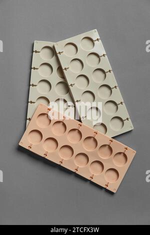 Stampi in silicone per cioccolatini, lecca lecca, dolci su sfondo grigio, vista dall'alto. Piatto di caramelle, piatto da forno. Concetto di pasticceria. Foto Stock