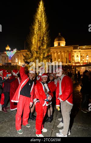 Persone che prendono parte a SantaCon a Trafalgar Square, che prevede di vestirsi da Babbo Natale e poi uscire in città per diffondere l'allegria natalizia. La Foto Stock