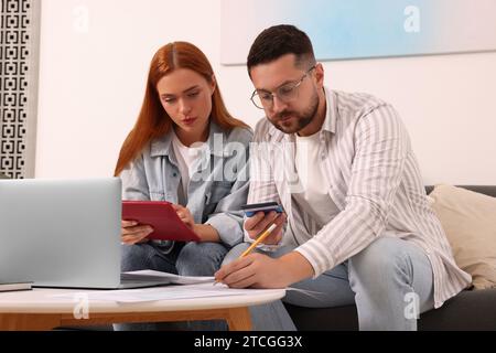 Coppia che compila il modulo di pagamento delle tasse al tavolo del soggiorno Foto Stock