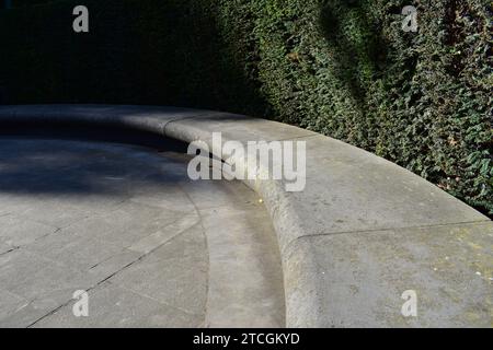 Sporgenza circolare in pietra con area pavimentata in pietra all'interno e siepe verde scuro intorno all'esterno Foto Stock