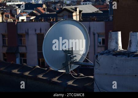 Vista posteriore di una parabola satellitare grigia sul tetto di un edificio con paesaggio urbano sullo sfondo Foto Stock