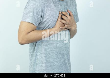 uomo asiatico che preme il petto con espressione dolorosa. Dolore grave, con attacco di cuore o crampi dolorosi, malattie cardiache. Foto Stock