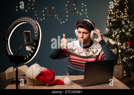 Blogger arabo che ha aperto la confezione con cuffie wireless e lo utilizza, il giovane influencer di Babbo Natale consiglia il prodotto e le riprese di un video Foto Stock