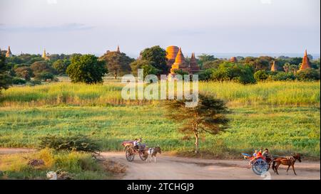 Una carrozza trainata da cavalli attraversa la vecchia regione del Myanmar, con lo sfondo di antichi templi buddisti Foto Stock