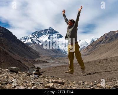 Uomo che salta per la gioia davanti alla vetta del Monte Everest, Tibet, Cina Foto Stock