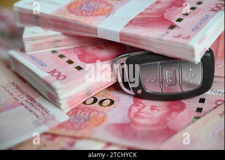 Pechino, Cina. 12 dicembre 2023. ILLUSTRAZIONE - Una chiave auto si trova su un tavolo sotto diverse banconote cinesi in renminbi (yuan). Credito: Johannes Neudecker/dpa/Alamy Live News Foto Stock