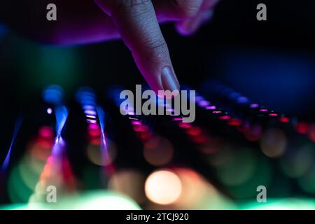 Videogiochi per computer, hacking, tecnologia, concetto Internet. Messa a fuoco selezionata. Tastiera per computer al neon con retroilluminazione a colori. Viene premuto un dito per primo piano Foto Stock