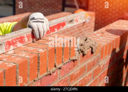 Muratori che posano mattoni su mortaio Foto Stock