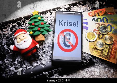 FOTOMONTAGE, smartphone mit Aufschrift Krise und durchgestrichenem Eurozeichen, Geldscheine, Weihnachtsmannfigur und Tannenbaum auf Computertastatur *** FOTOMONTAGGIO, smartphone con iscrizione di crisi e segno dell'euro barrato, banconote, figura di Babbo Natale e albero di Natale sulla tastiera del computer Foto Stock