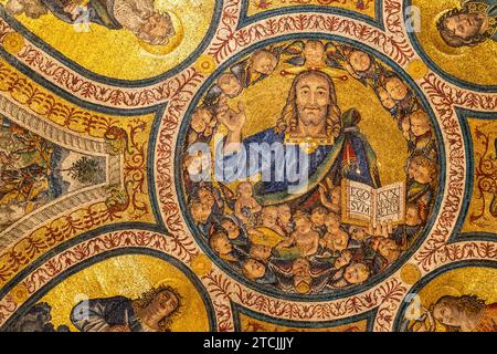 Primo piano sul mosaico dorato religioso del soffitto della basilica in Italia che mostra un sorriso Gesù circondato da un grande gruppo di bambini Foto Stock