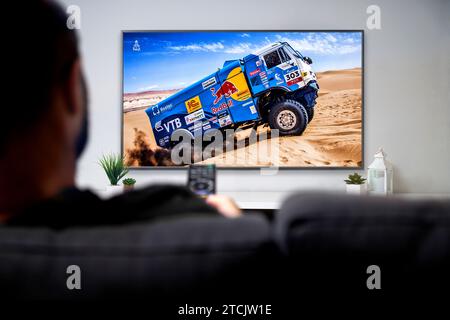 Uomo che guarda la gara di rally Dakar su una smart TV. Concetto di trasmissione Sports Live. ROSARIO, ARGENTINA - 2 DICEMBRE 2023. Foto Stock