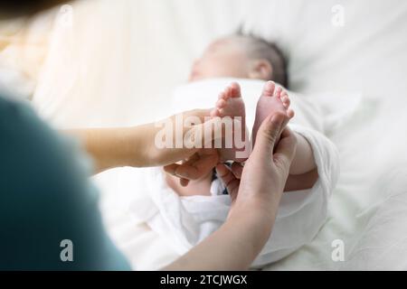 Le mani della madre massaggiano i piedi del neonato Foto Stock